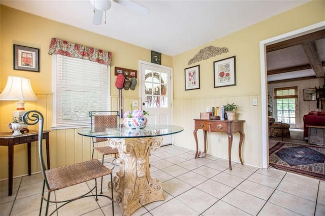 dining room featuring a wainscoted wall, light tile patterned flooring, and a ceiling fan