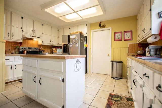 kitchen featuring stainless steel fridge, range, light tile patterned floors, and white cabinetry