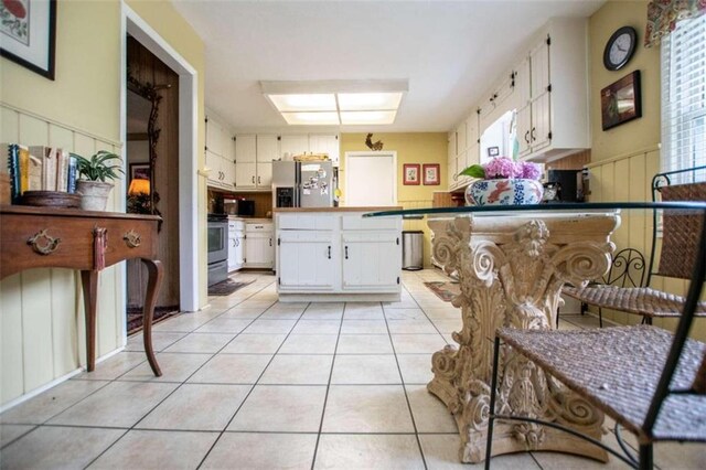 kitchen featuring light tile patterned floors, appliances with stainless steel finishes, a skylight, and white cabinetry