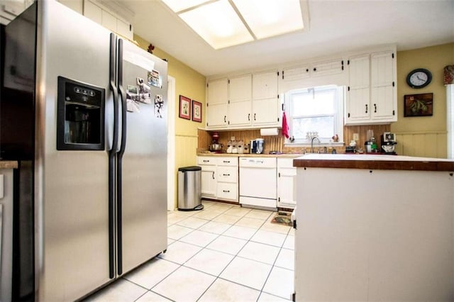 kitchen with light tile patterned floors, tasteful backsplash, dishwasher, stainless steel fridge with ice dispenser, and white cabinets