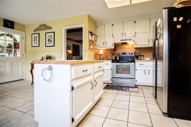 kitchen featuring light tile patterned floors, range with electric stovetop, stainless steel refrigerator, and white cabinets