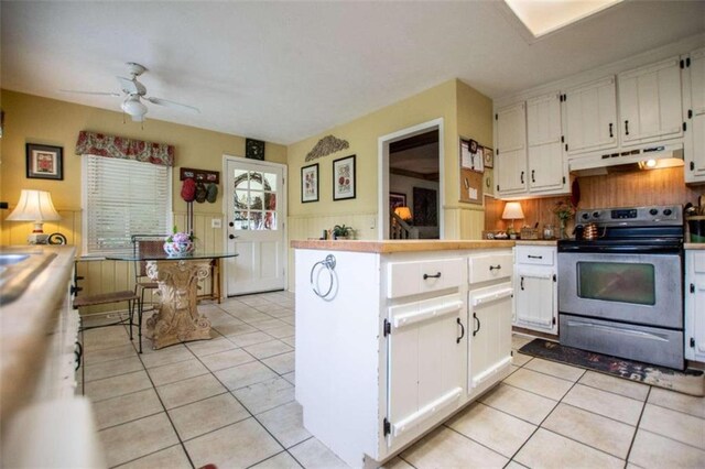 kitchen featuring ceiling fan, electric stove, light tile patterned floors, and white cabinetry