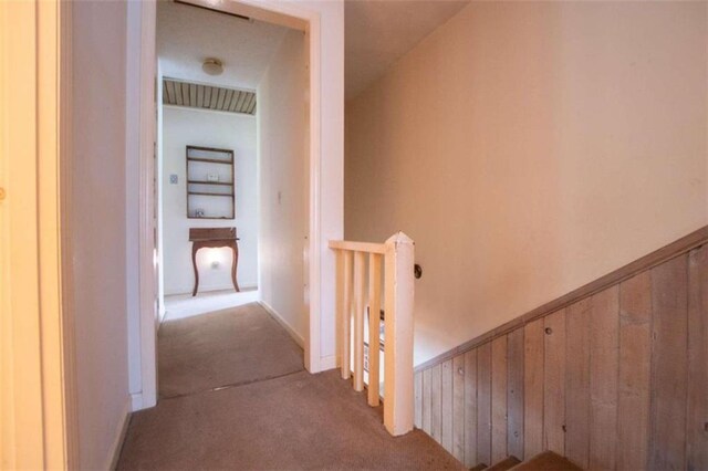 corridor featuring a wainscoted wall, carpet flooring, an upstairs landing, and wooden walls