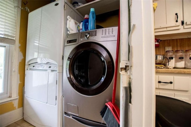 clothes washing area with a wealth of natural light, laundry area, washer and clothes dryer, and baseboards