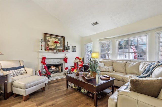 living room featuring a high end fireplace, hardwood / wood-style floors, and vaulted ceiling