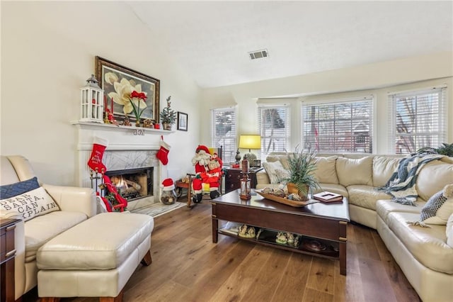 living room with a premium fireplace, wood-type flooring, and vaulted ceiling