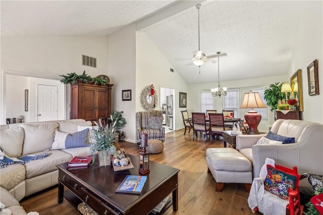 living room featuring high vaulted ceiling, ceiling fan with notable chandelier, and hardwood / wood-style flooring