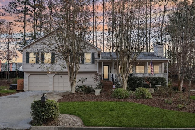 tri-level home with a yard, a porch, and a garage