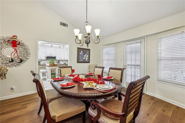 dining room with plenty of natural light, dark wood-type flooring, and vaulted ceiling