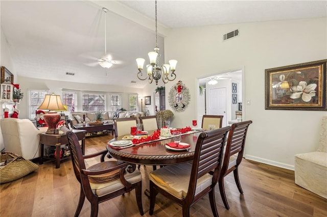 dining room with ceiling fan with notable chandelier, hardwood / wood-style floors, and lofted ceiling with beams