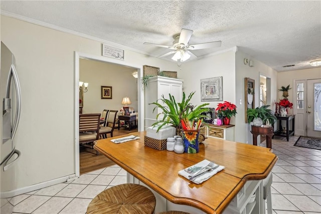 dining space featuring ceiling fan, crown molding, light tile patterned floors, and a textured ceiling