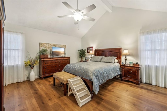 bedroom with multiple windows, hardwood / wood-style flooring, ceiling fan, and beamed ceiling