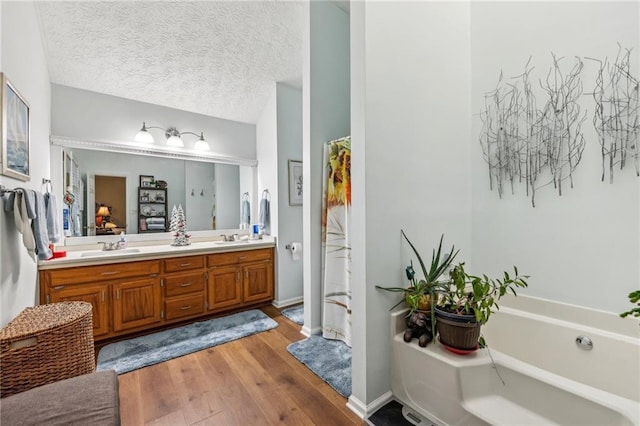 bathroom featuring a bathing tub, vanity, wood-type flooring, and a textured ceiling