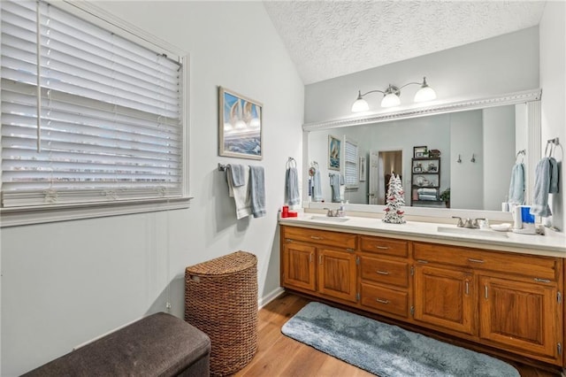 bathroom featuring hardwood / wood-style flooring, vanity, a textured ceiling, and vaulted ceiling