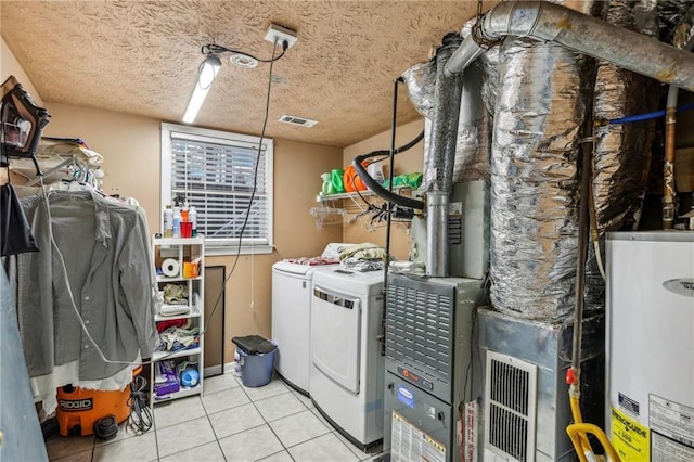 washroom with gas water heater, light tile patterned floors, a textured ceiling, and washing machine and clothes dryer