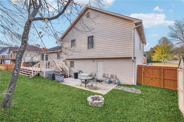 rear view of property featuring a lawn, a patio area, a deck, and an outdoor fire pit