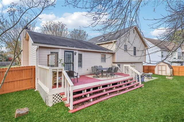 back of house with a lawn, a storage unit, and a deck