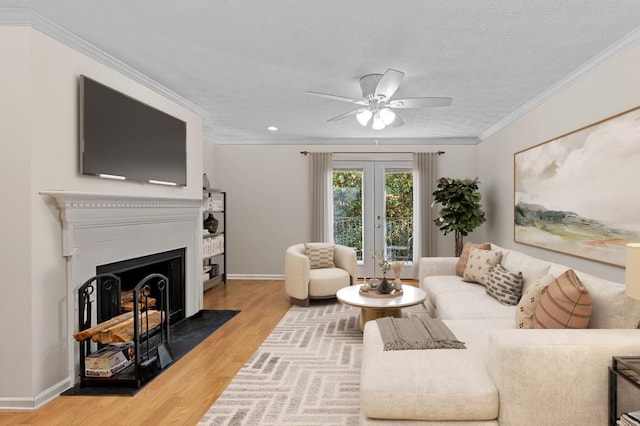 living area featuring wood finished floors, ceiling fan, french doors, baseboards, and a fireplace with flush hearth