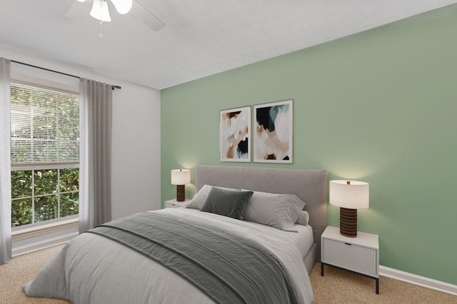 bedroom featuring baseboards, ceiling fan, multiple windows, and carpet flooring