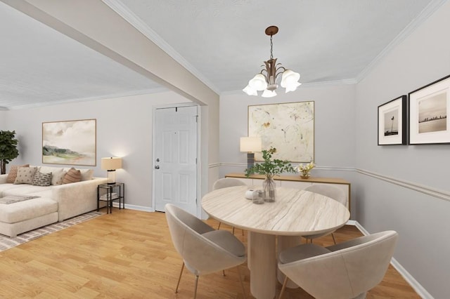 dining space featuring baseboards, ornamental molding, a notable chandelier, and light wood finished floors