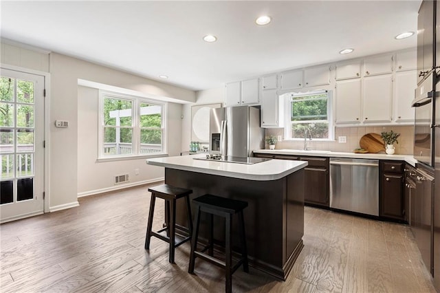 3131 Garden Lane Dr, Marietta, GA 30062 - kitchen featuring appliances with stainless steel finishes, light countertops, a center island, light wood finished floors, and plenty of natural light