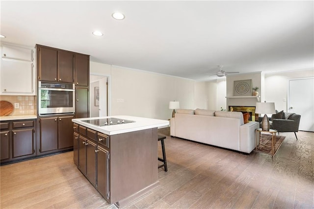 3131 Garden Lane Dr, Marietta, GA 30062 - kitchen with stainless steel oven, a kitchen breakfast bar, ceiling fan, light wood-style floors, and dark brown cabinets
