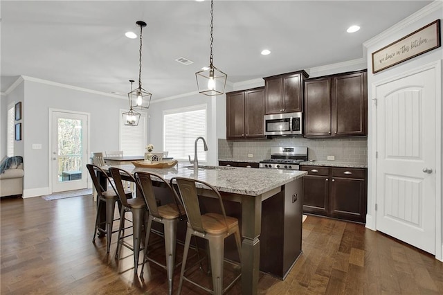 kitchen featuring a kitchen breakfast bar, stainless steel appliances, sink, pendant lighting, and a center island with sink