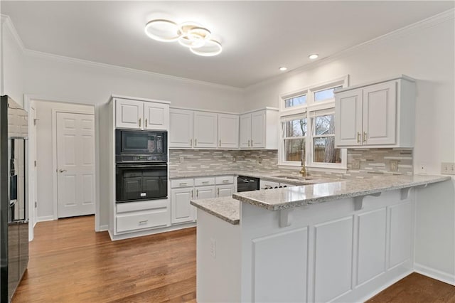 kitchen featuring white cabinetry, light stone countertops, black appliances, and kitchen peninsula