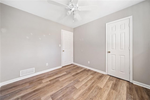 spare room with visible vents, ceiling fan, baseboards, and wood finished floors