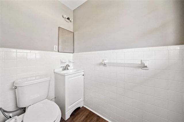 bathroom featuring a wainscoted wall, tile walls, toilet, vanity, and wood finished floors