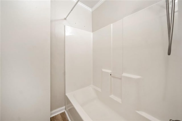 bathroom with ornamental molding, a shower, and wood finished floors