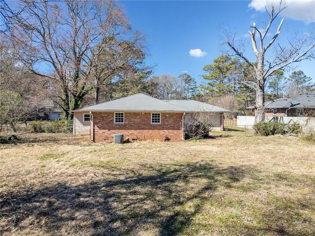 view of home's exterior featuring a yard, brick siding, central AC, and fence