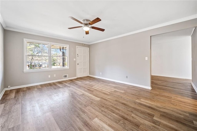 empty room with visible vents, crown molding, baseboards, and wood finished floors