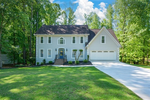 colonial house featuring driveway, a front yard, stucco siding, and an attached garage