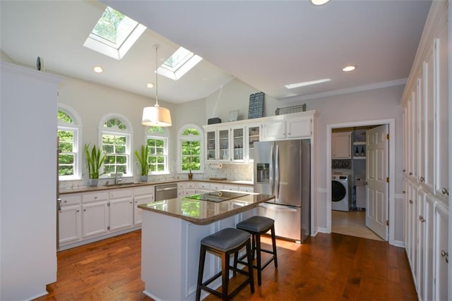 kitchen featuring stainless steel appliances, washer / clothes dryer, a skylight, a sink, and white cabinetry