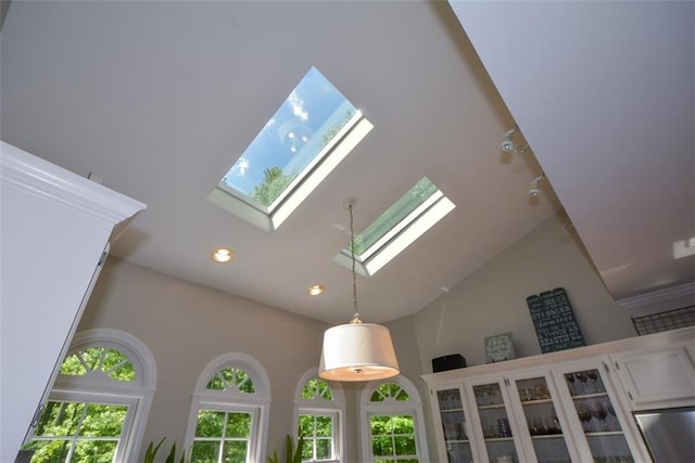 detailed view of a skylight, recessed lighting, glass insert cabinets, decorative light fixtures, and white cabinets