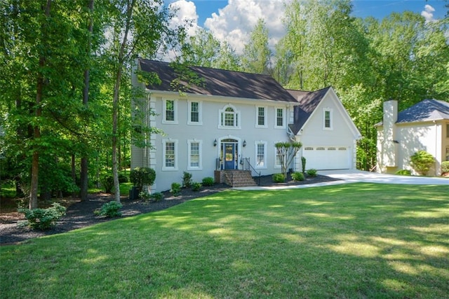 colonial home featuring a garage, concrete driveway, and a front lawn