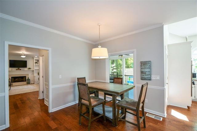 dining room featuring dark wood-style floors, ornamental molding, baseboards, and a fireplace