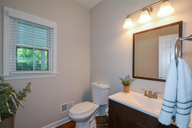 bathroom featuring toilet, vanity, and baseboards