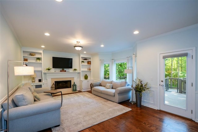 living room with ornamental molding, dark wood-style floors, recessed lighting, a fireplace, and built in features