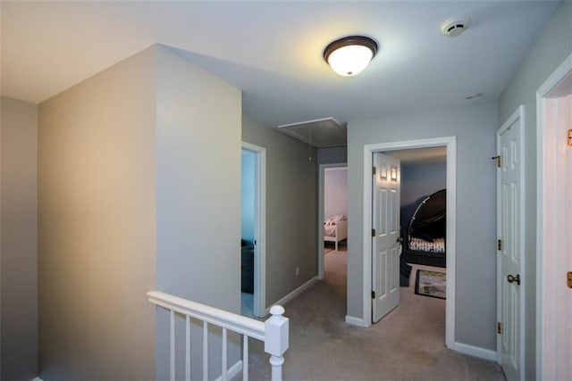 corridor with attic access, carpet, an upstairs landing, and baseboards