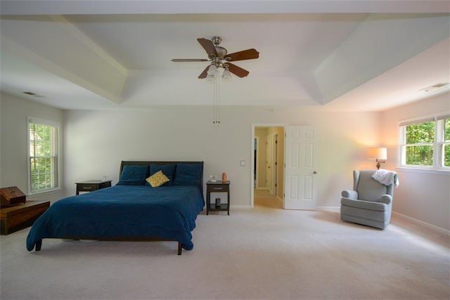 carpeted bedroom featuring a raised ceiling, baseboards, and ceiling fan
