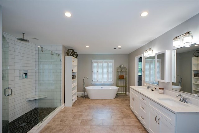 bathroom with a stall shower, a freestanding bath, recessed lighting, double vanity, and baseboards