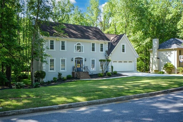 colonial inspired home featuring concrete driveway, a front yard, and stucco siding