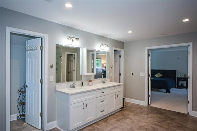ensuite bathroom with double vanity, baseboards, and recessed lighting