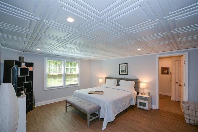 bedroom featuring baseboards, an ornate ceiling, wood finished floors, and recessed lighting