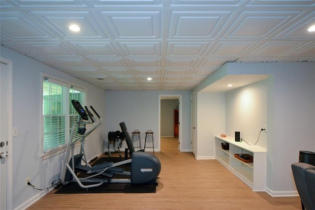 exercise room featuring recessed lighting, baseboards, light wood-style floors, and an ornate ceiling