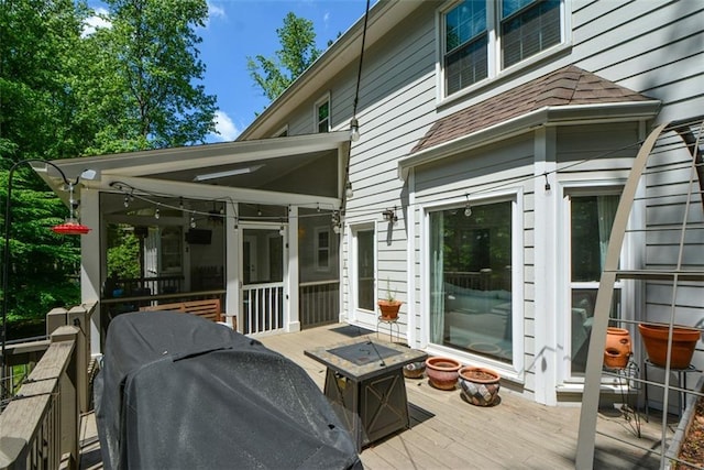 wooden deck with an outdoor fire pit, a sunroom, and grilling area