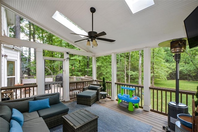 sunroom / solarium with a skylight, vaulted ceiling, a ceiling fan, and an outdoor living space