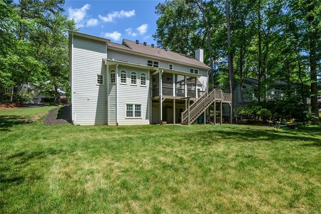 back of house featuring a sunroom, stairway, a chimney, a lawn, and a wooden deck